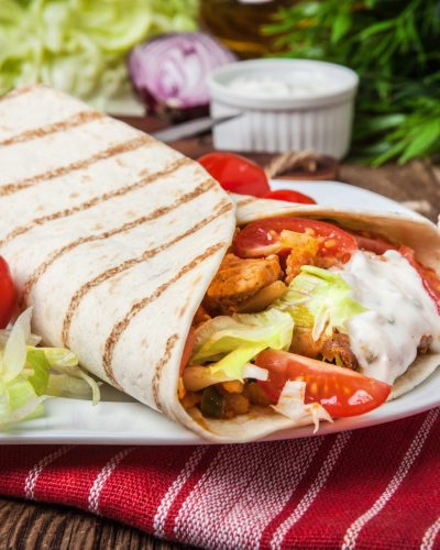 Tasty fresh wrap sandwich with chicken, vegetables and tzatziki sauce.